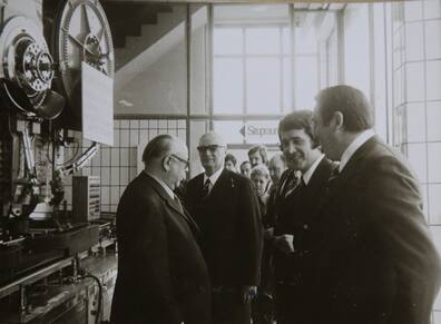 Men in suits beside industrial machinery in a vintage photograph from the Liebelt family business